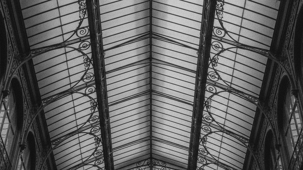 Verrière en fer forgé et verre d'un passage couvert parisien en contre-plongée, motifs entrelacés du marché de l'art